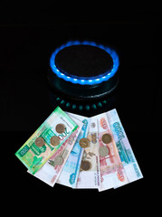 Payment by European consumers for Russian natural gas in rubles. Banknotes of Russian rubles of different denominations and coins next to a gas burner on a black background. Fuel price concept