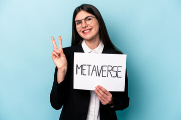 Young caucasian business woman holding a metaverse placard isolated on blue background joyful and...