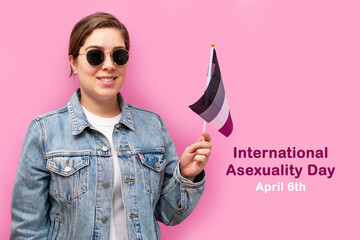 International Asexuality Day. Happy girl hold asexual flag, on pink background.