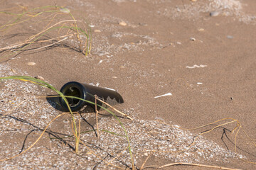 Glass bottle lying on the sand near the beach. Let's take care of the planet