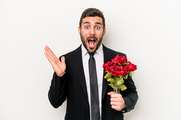 Young caucasian man holding a bouquet of flowers isolated on white background surprised and shocked.