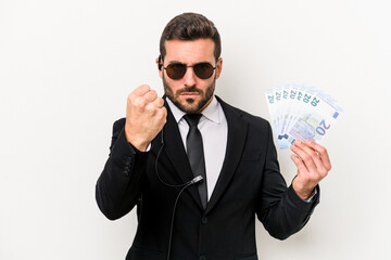 Young caucasian bodyguard man holding banknotes isolated on white background showing fist to...