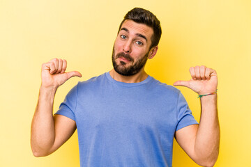 Young caucasian man isolated on yellow background feels proud and self confident, example to follow.