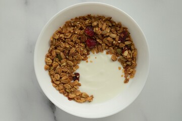 Bowl with granola and yougurt, marble background, flat lay