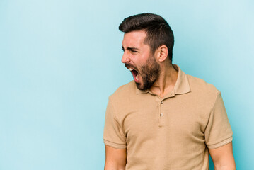 Fototapeta premium Young caucasian man isolated on blue background shouting very angry, rage concept, frustrated.