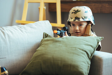 Little boy playing soldiers in living room. In his imagination the boy are defending the encircled city of Bastogne aganist the enemy.  Entertainment for kids indoors. Offline games.