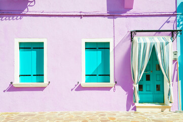 Blue windows and door on the violet wall of the house. Colorful architecture of Burano island, Venice, Italy