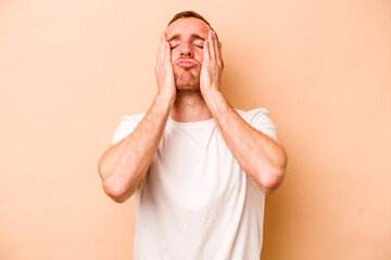 Young caucasian man isolated on beige background whining and crying disconsolately.