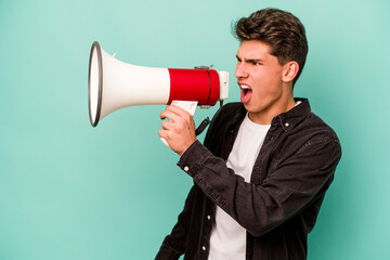 Young caucasian man holding a megaphone isolated on white background raising fist after a victory, winner concept.