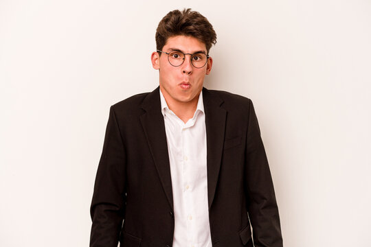Young caucasian business man isolated on white background shrugs shoulders and open eyes confused.