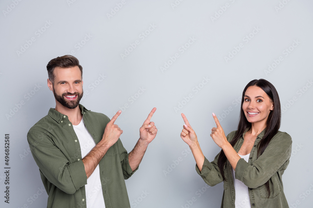 Aufkleber portrait of attractive cheerful couple demonstrating copy blank empty space ad isolated over grey pa