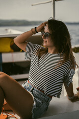 A young woman in sunglasses travels on a boat in the ocean.