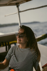 A young woman in sunglasses travels on a boat in the ocean.