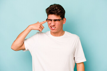 Fototapeta premium Young caucasian man isolated on blue background covering ears with hands.