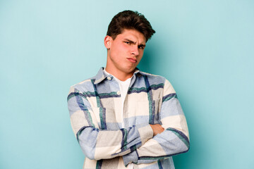 Young caucasian man isolated on blue background unhappy looking in camera with sarcastic expression.