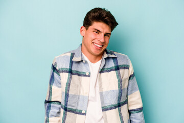 Fototapeta premium Young caucasian man isolated on blue background laughs and closes eyes, feels relaxed and happy.