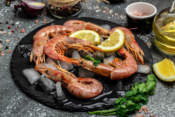 Red Argentine shrimps with ice and lemon, Wild shrimps, ocean jumbo shrimps on a dark background....