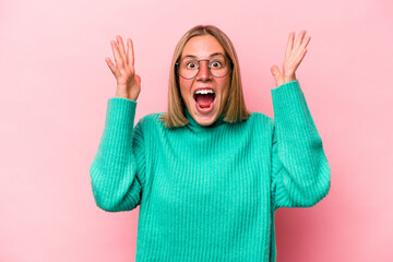 Young caucasian woman isolated on pink background celebrating a victory or success, he is surprised and shocked.