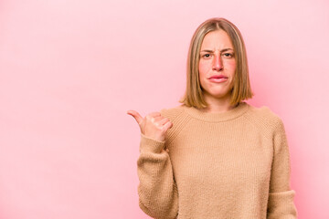 Young caucasian woman isolated on pink background shocked pointing with index fingers to a copy space.