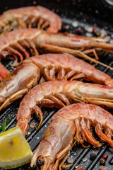 Grilled tiger shrimps with spice, lemon and garlic in a frying pan on a dark background. Prawns fried, Seafood appetizer vertical image. top view