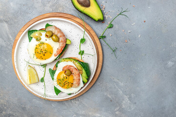 Toast with wholemeal bread, soft fried egg, spinach, avocado, shrimps on gray background, Ketogenic breakfast. superfood concept. Healthy, clean eating. Top view