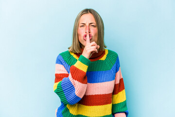 Young caucasian woman isolated on blue background keeping a secret or asking for silence.