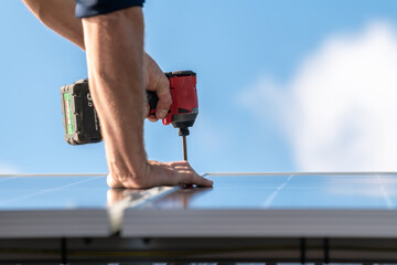 Unidentified man attaching solar panel to the house roof rack with a cordless screwdriver