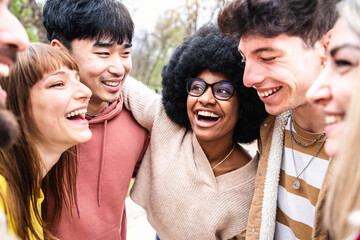 Multiracial friends hugging together outdoors - Happy young people enjoying day out walking outside...