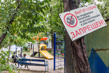 No dogs allowed warning sign in courtyard. Dog prohibition sign. Inscription "Dogs walking is forbidden" (in Russian) to prevent dogs walking in area. Russia, Vladivostok.