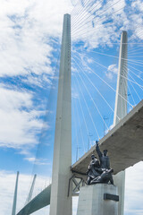 Russia, Vladivostok, June 05, 2021. View on Golden Bridge and monument to Merchant Navy from city downtown. Golden Bridge is the most famous sight of Vladivostok. Welcome to Vladivostok concept.