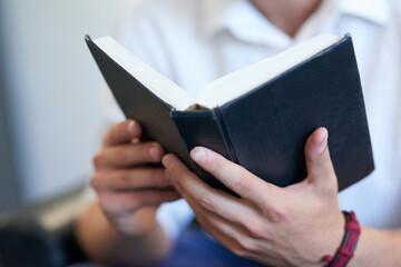 Keeping his faith strong. Shot of an unrecognizable young man reading the bible at work.