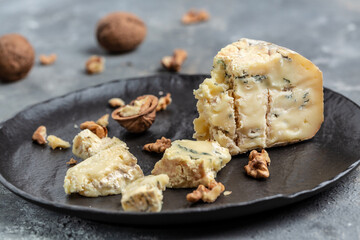 Danish blue cheese. Tasty blue cheese on a dark plate. Dorblu cheese pieces. Food recipe background. Close up