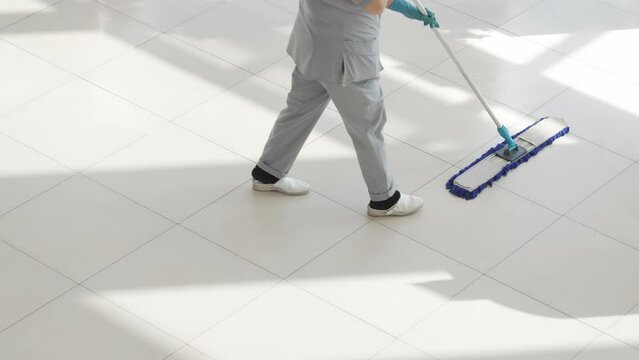 a female cleaner washes floors with a mop in the office or sales floor.