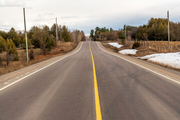 Fototapeta premium A rural roadside as spring arrives, some remnant snow visible. Shot in the farm country of the Ottawa Valley (Ontario, Canada) in early April.