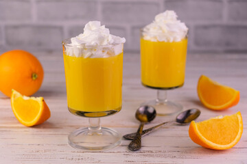 Orange curd with whipped cream on a white wooden background.