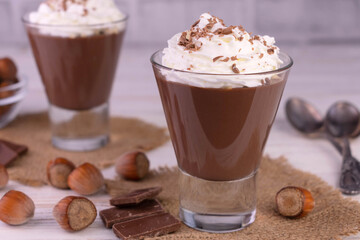 Chocolate mousse with hazelnuts and cream on a white wooden background.	