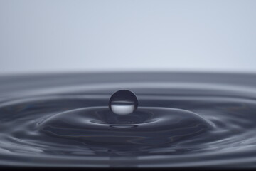 Fototapeta Kropla nad taflą wody na jasnym tle obraz