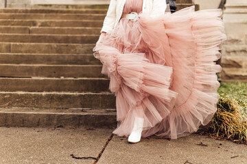 Closeup shot of an anonymous female wearing a pink tulle dress and leaning on the stairs