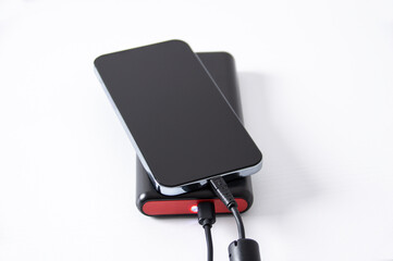 Smartphone and auxiliary battery with charger on the white table in an office