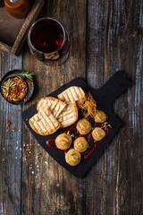 Serving board composition with pate and toast, red sauce and onion chips. On a wooden table is a box with spices and herbs, a glass of red wine. Menu for restaurant, bar, cafe. Top view.