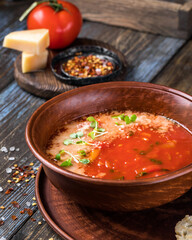 Brown plate of tomato soup with parmesan, microgreens and toast. On a wooden background spices, cheese, tomato. For the menu of the restaurant, cafe, bar. Close up.