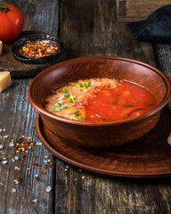 Brown plate of tomato soup with parmesan, microgreens and toast. On a wooden background spices, cheese, tomato. For the menu of the restaurant, cafe, bar. Close up.
