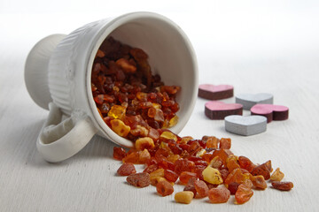 Raw amber in a white cup scattered on a wooden white table
