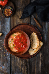 Brown plate of tomato soup with parmesan, microgreens and toast. On a wooden background spices, cheese, tomato. For the menu of the restaurant, cafe, bar. Top view.