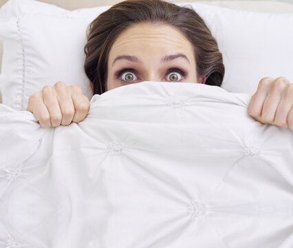 Did You Hear That. A Young Woman Peeking Out From Under Her Ned Sheet With A Frightened Expression.