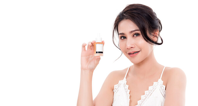 Asian Young Beautiful Woman Smiling She's Holding Bottle Serum Hair Or Skin Care Near Face For Present Product Isolated On Over White Background, Beauty Salon Concept