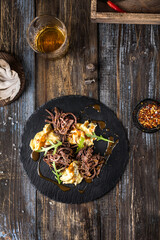 On a round serving board, mashed potatoes with beef in mushroom sauce, with herbs. On a wooden table is spices, mushrooms, a glass of cognac. Top view. For the menu of a restaurant, cafe, bar