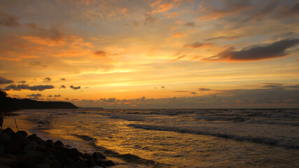 Beautiful sunset over the sea with orange reflexes on clouds and sea foam