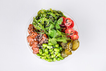 Poke bowl with rice, salmon beans edamame chukka, cherry tomatoes pickled cucumbers sesame and parsley. Plastic tableware for delivery. Top view. White background.