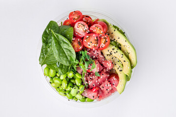Poke bowl with rice, tuna, edamame beans, avocado, cherry tomatoes and spinach on a white background. Top view.